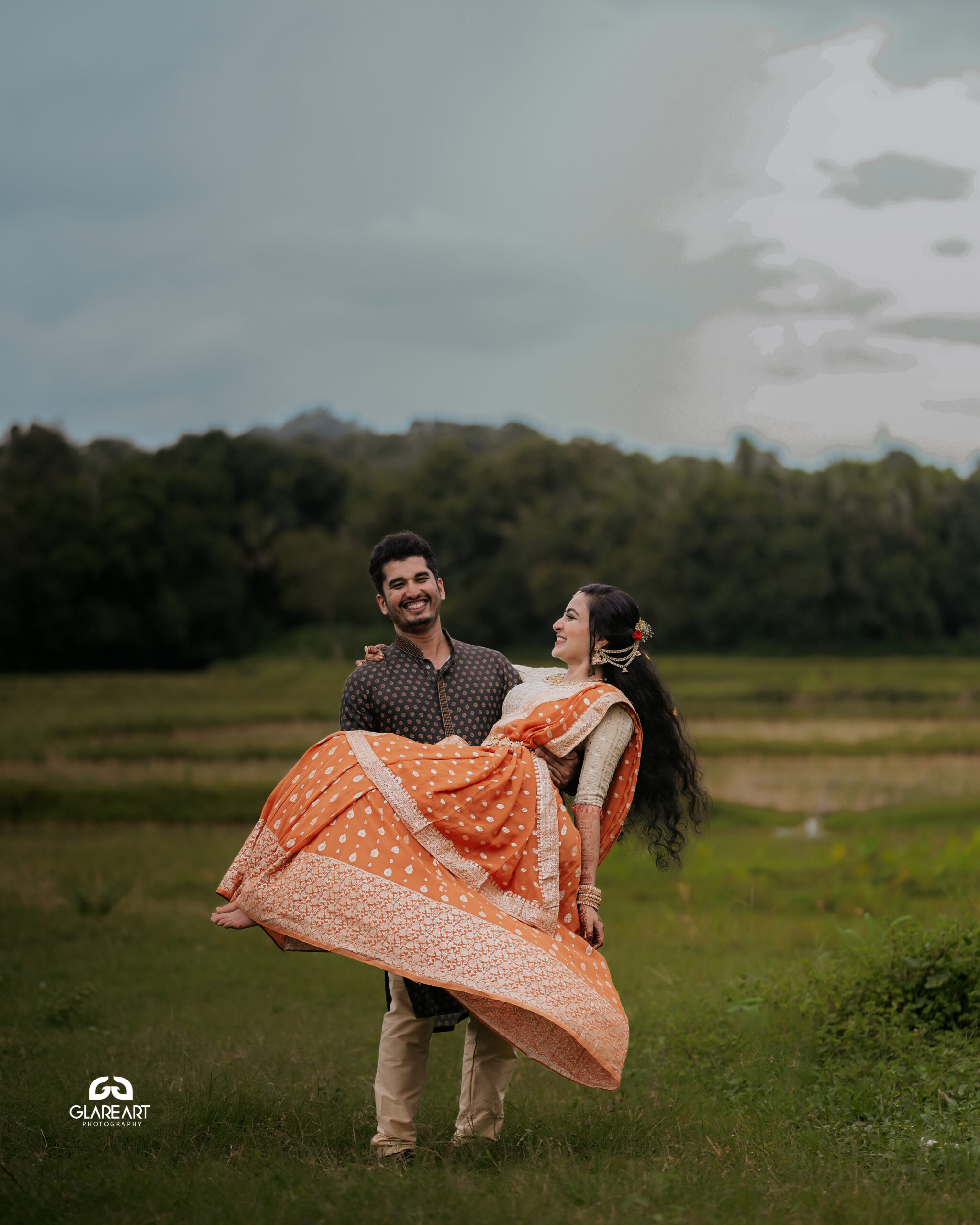 This is a lovely engagement-style photograph set in a natural outdoor location. The scene captures joyful and candid moments, emphasizing cultural attire- best wedding photography in Palakkad-wedding photography Palakkad