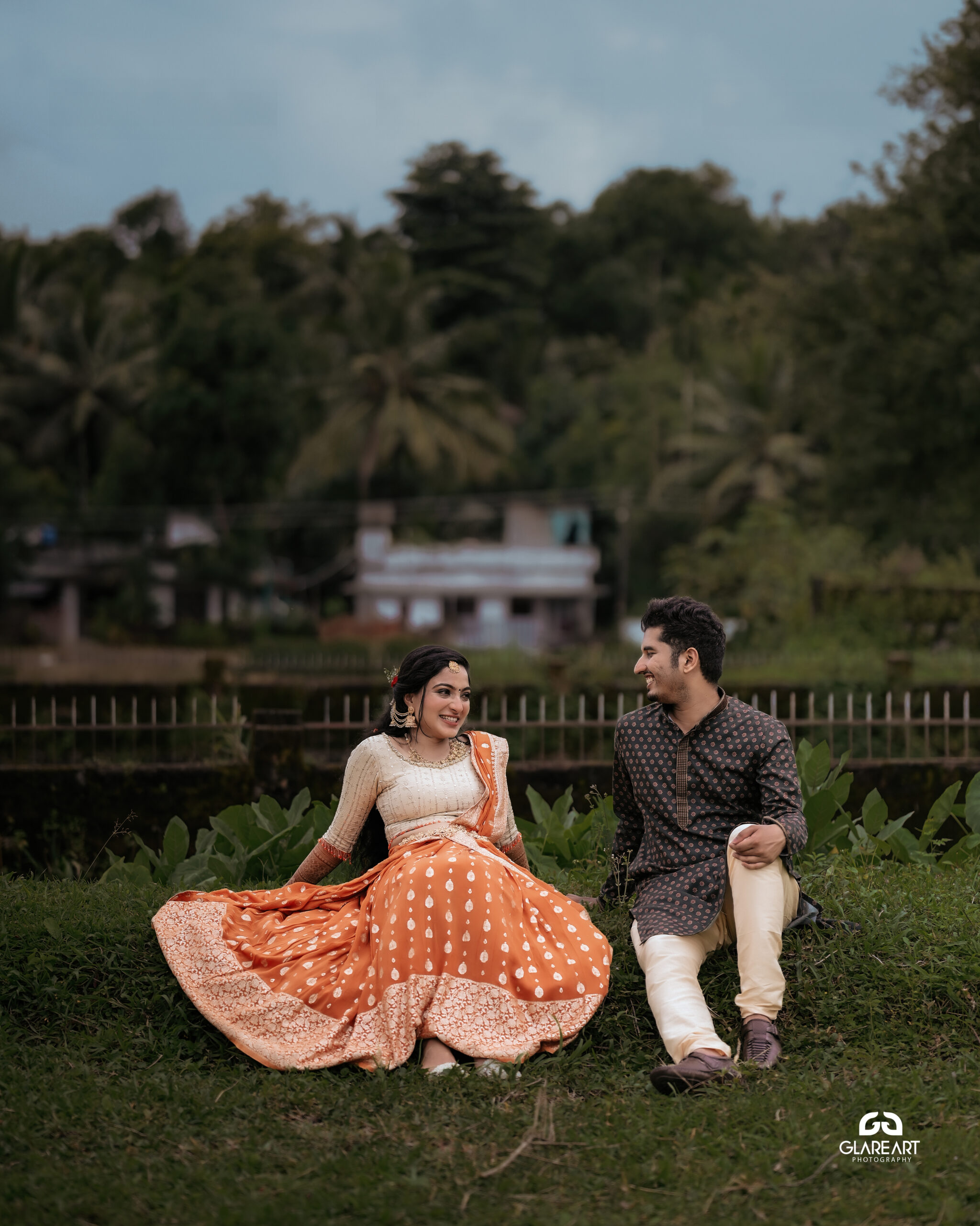 This is a lovely engagement-style photograph set in a natural outdoor location. The scene captures joyful and candid moments, emphasizing cultural attire- best wedding photography in Palakkad-wedding photography Palakkad